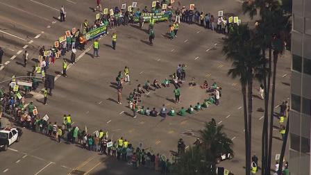 About 25 protesters blocked traffic by sitting in a circle in the middle of the intersection at Wilshire and Westwood boulevards on Friday, July 26, 2013. (KABC Photo)