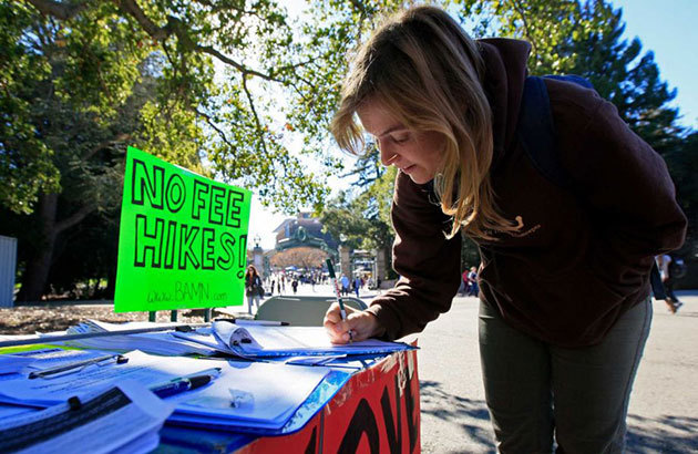 UC Berkeley student Allie Lalor signs a petition before joining in a walk-out of classes, protesting a recent approval of UC tuition hikes, on Nov. 24 at UC Berkeley. Photo: Jessica Christian / The Chronicle